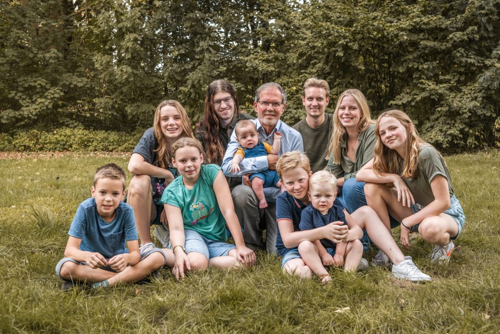 Grote familie zit samen in het gras bij een groene locatie