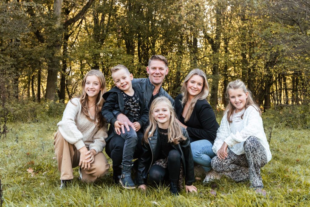 Gezin met kinderen zit samen voor een bosrand