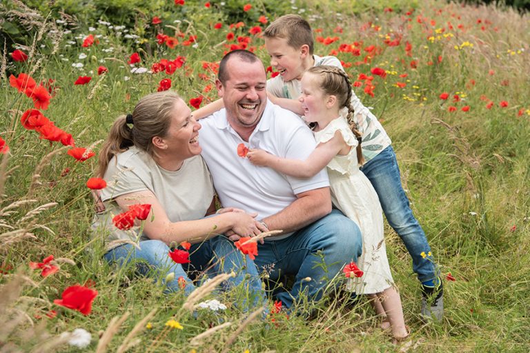 Ouders en kinderen lachen samen tussen de klaprozen