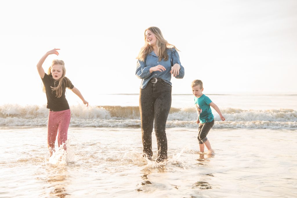 Moeder en kinderen spetteren in de zee